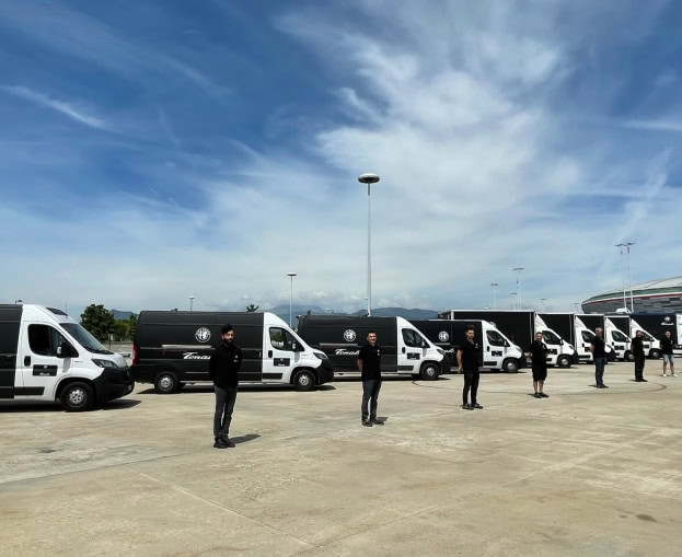 Furgoni di consegna con personale in fila in un parcheggio all'aperto.
