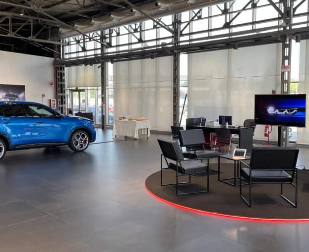 Showroom con auto Alfa Romeo Tonale e area lounge moderna.