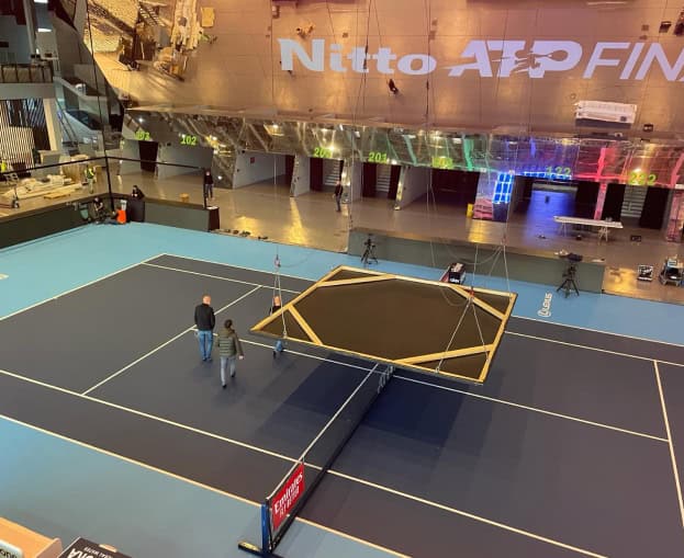Indoor tennis court setup at ATP Finals Turin with a trampoline in the center.