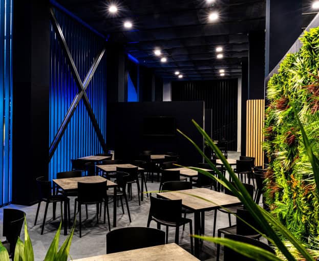 Modern event space with black furniture and green plant decor for ATP Finals Turin.