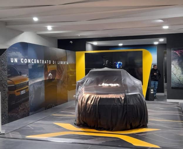 Jeep Avenger covered with a black cloth at an indoor event.