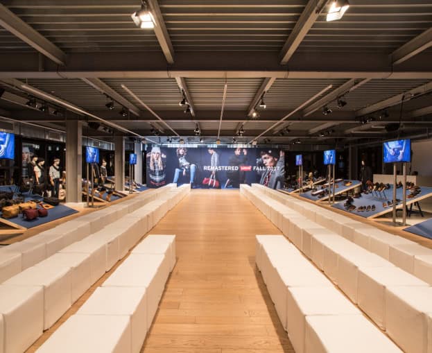Interno di uno spazio evento con sedute bianche e schermi TV.