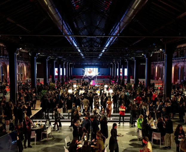 Large event hall with many attendees and a stage at the front.