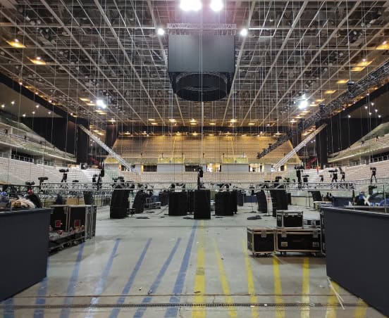 Interno di un grande spazio per eventi con attrezzature e palco in preparazione.